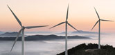 Image: Three wind turbines on a mountain top at dawn